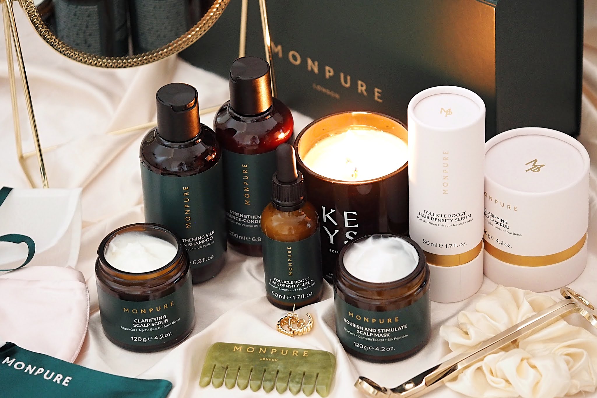 Monpure London hair care products including shampoo, conditioner, scalp scrub, and serum, displayed with a candle and accessories.